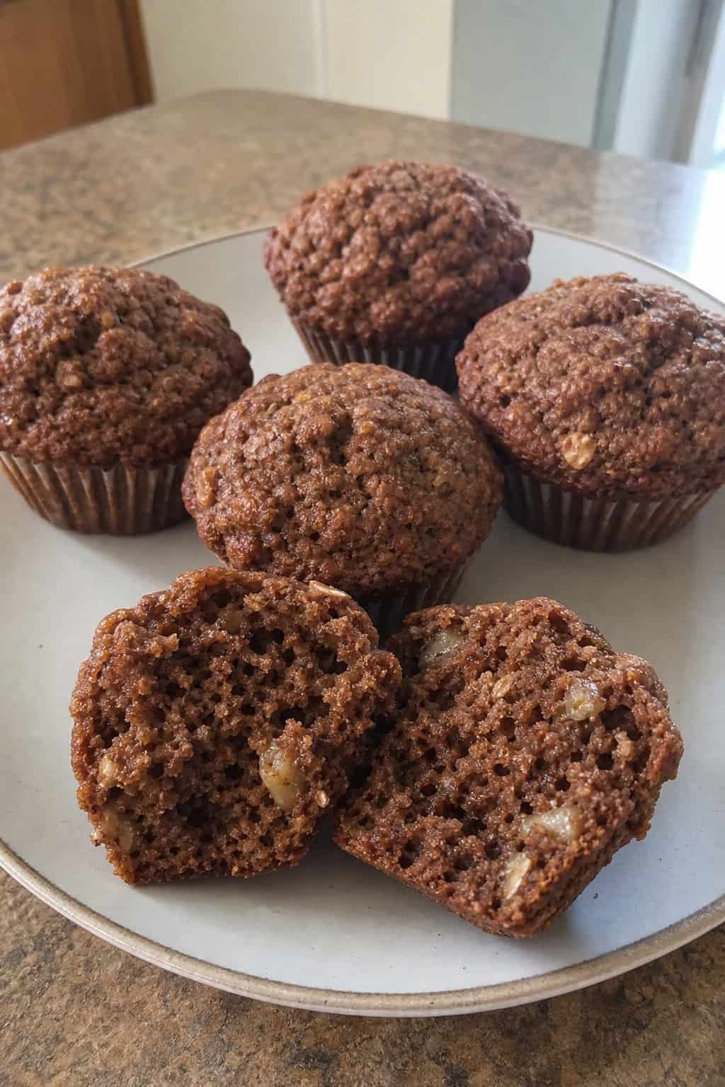 Freshly baked breakfast muffins made with brownie mix, oats, and banana arranged on a wooden board with banana slices and oats nearby.