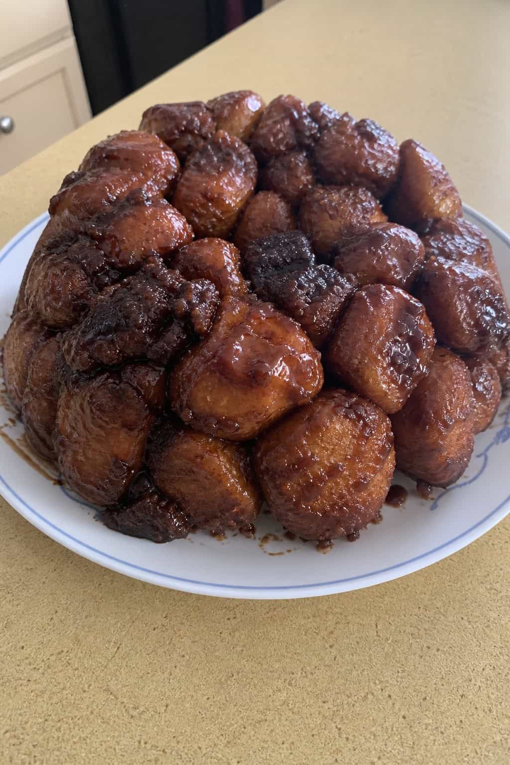 A freshly baked monkey bread made with brownie mix and cinnamon rolls on a wooden board, surrounded by baking ingredients.