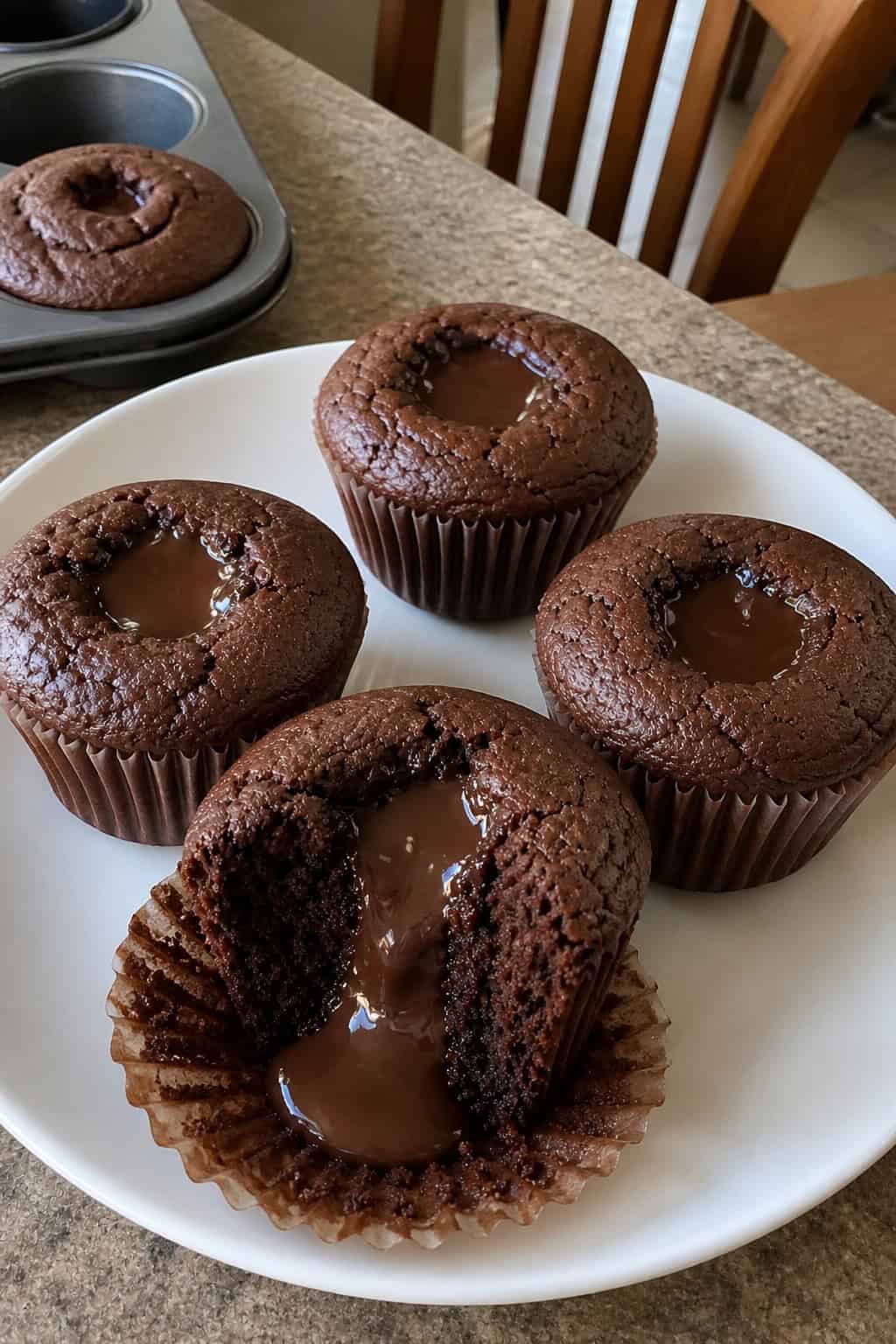 Close-up of several brownie lava cupcakes with melted chocolate centers on a wooden surface.