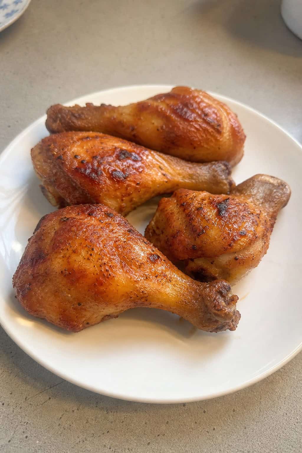Deep golden chicken legs on a weathered wooden cutting board with a side of herb-flecked dipping sauce and scattered fresh thyme.