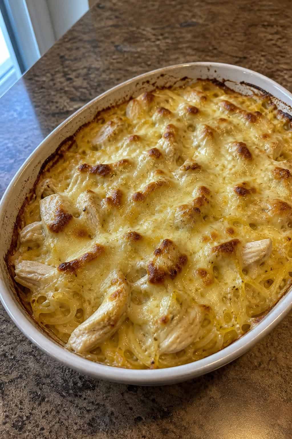 22 Chicken and Spaghetti Squash Recipes You’ll Love to Try Tonight! 9 A baked casserole dish filled with chicken Alfredo spaghetti squash topped with melted cheese and garnished with parsley on a wooden table.