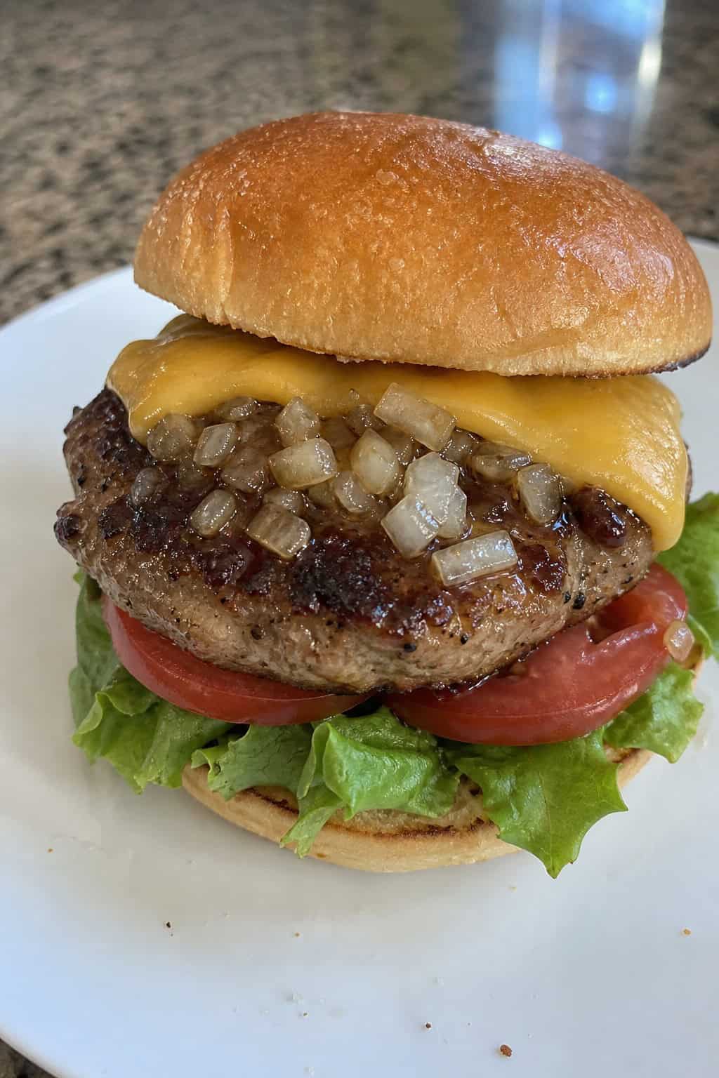 A juicy turkey burger with grated onion and Worcestershire sauce on a toasted bun with lettuce and tomato.