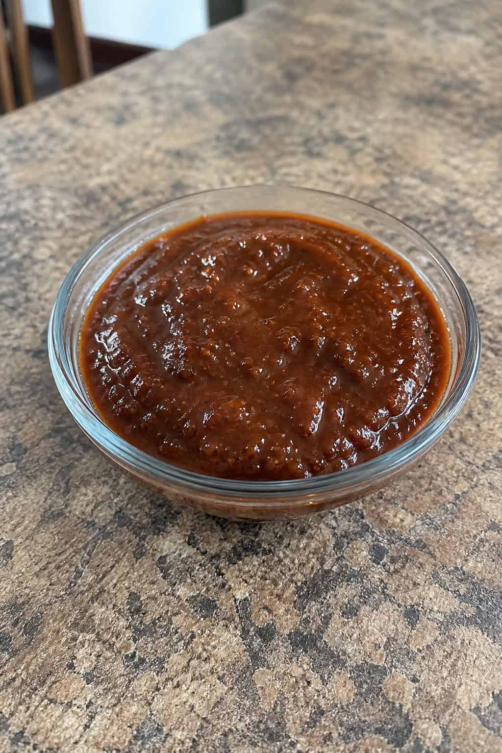 18 Chipotle Copycat Recipes to Make at Home 18 A bowl of chipotle barbecue sauce surrounded by chipotle peppers, garlic, cilantro, lime wedges, and paprika on a wooden table.