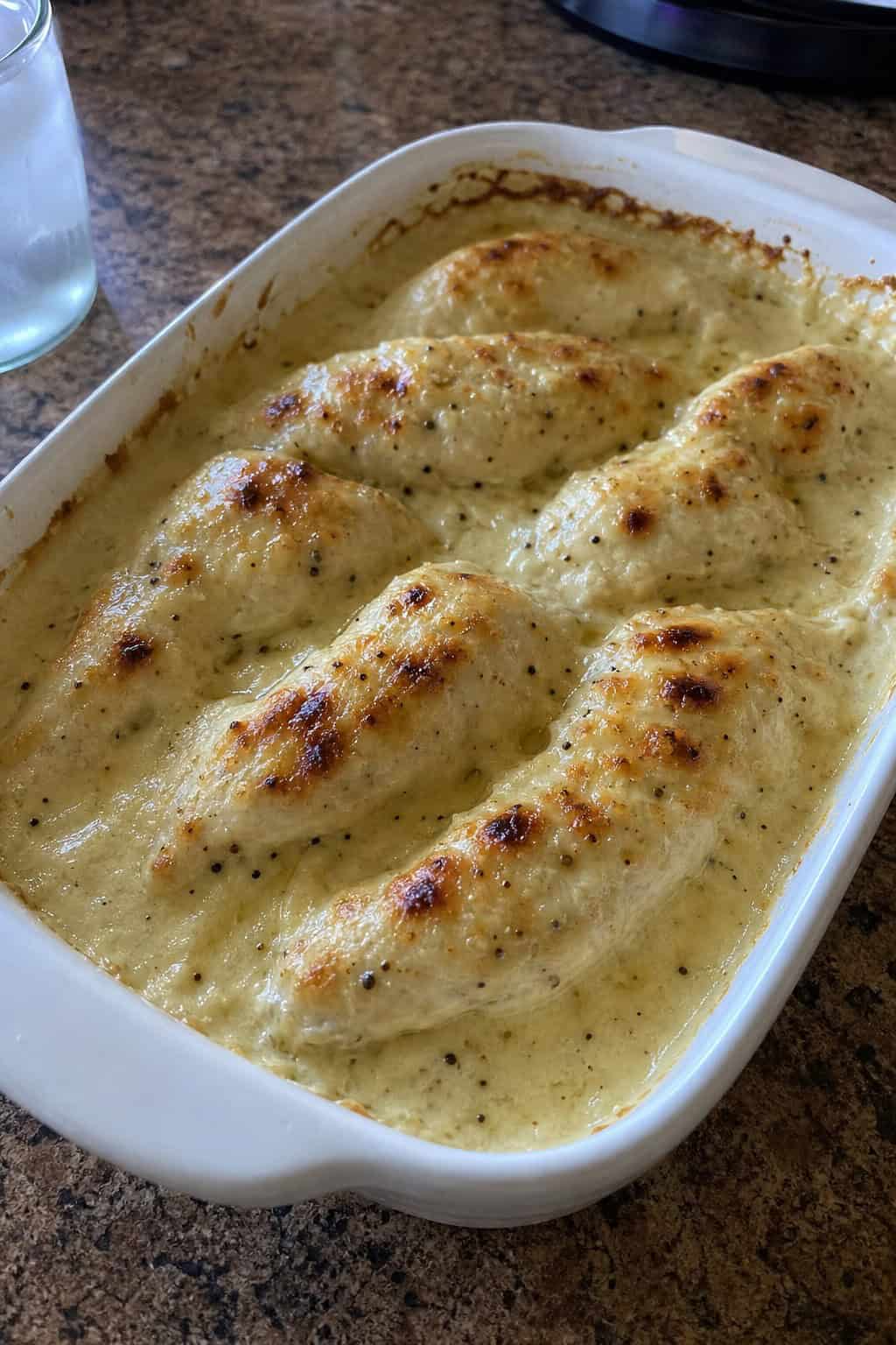 A creamy chicken tenderloin Alfredo bake in a white casserole dish, bubbling at the edges and topped with melted mozzarella and chopped parsley.