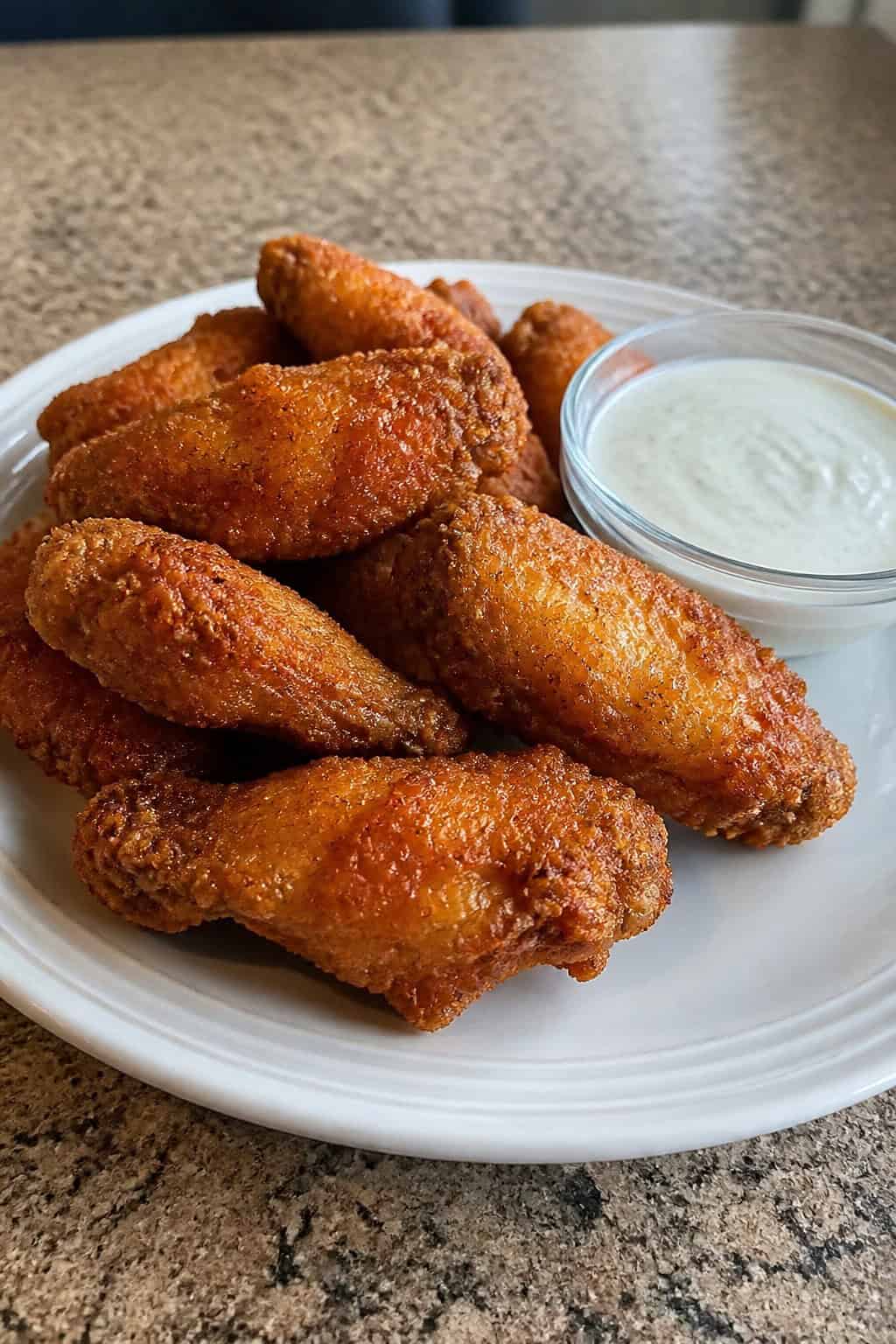 22 Chicken Wing Recipes for Game Day and Beyond 10 A plate of crispy buttermilk fried chicken wings with a bowl of ranch dressing on a wooden table.