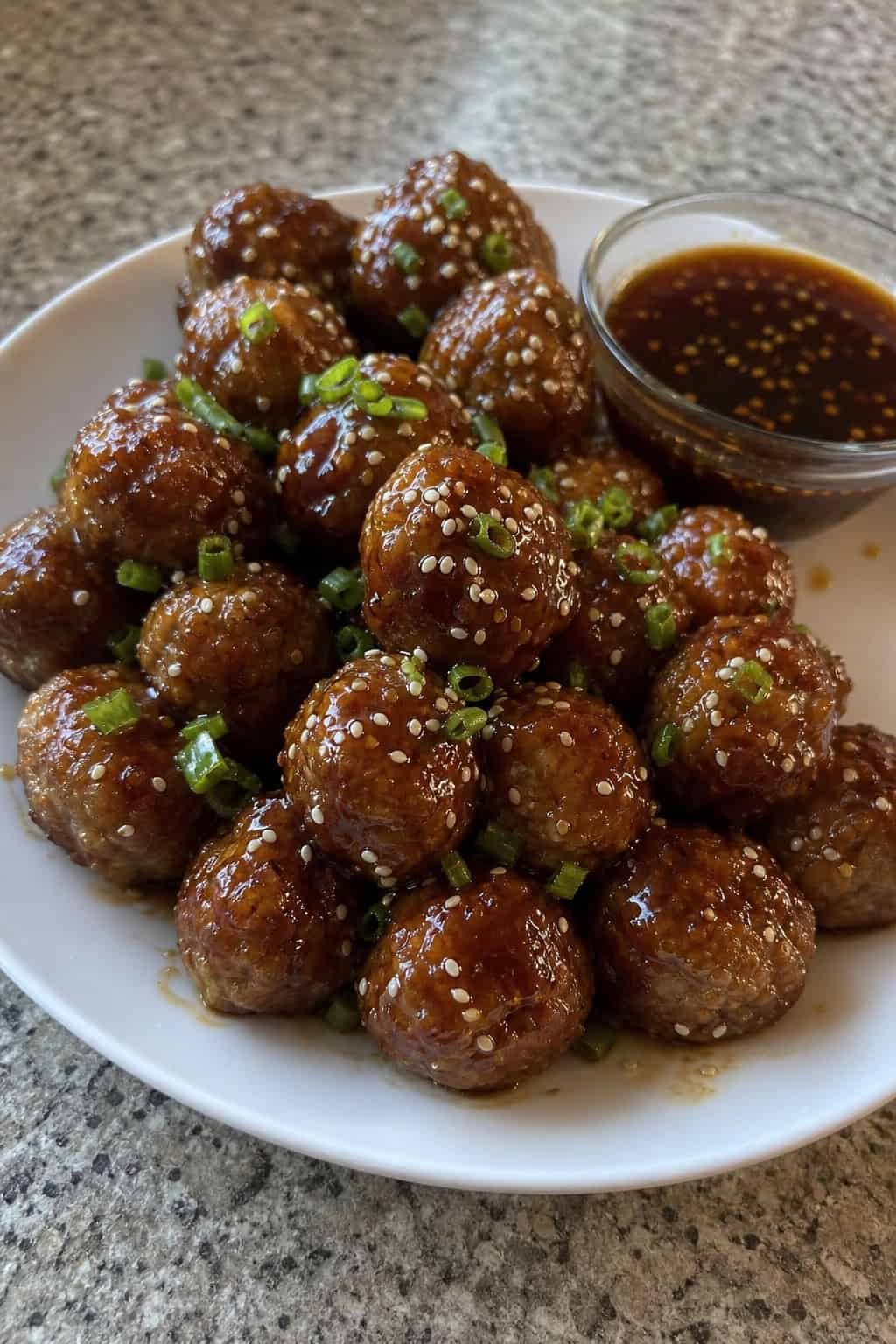23 Make-Ahead Appetizers for Easy Hosting: Wow Your Guests Without Breaking a Sweat 11 A platter of honey-sesame meatballs with a bowl of dipping sauce on a table.