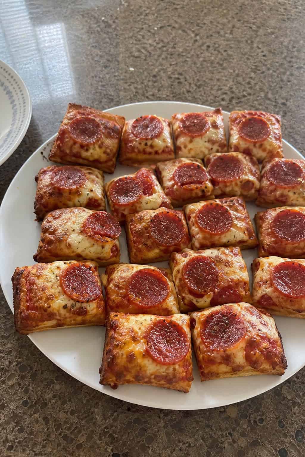 22 Easy Costco Party Appetizers 11 A serving platter with Kirkland frozen pizza cut into small square party bites arranged for a party.