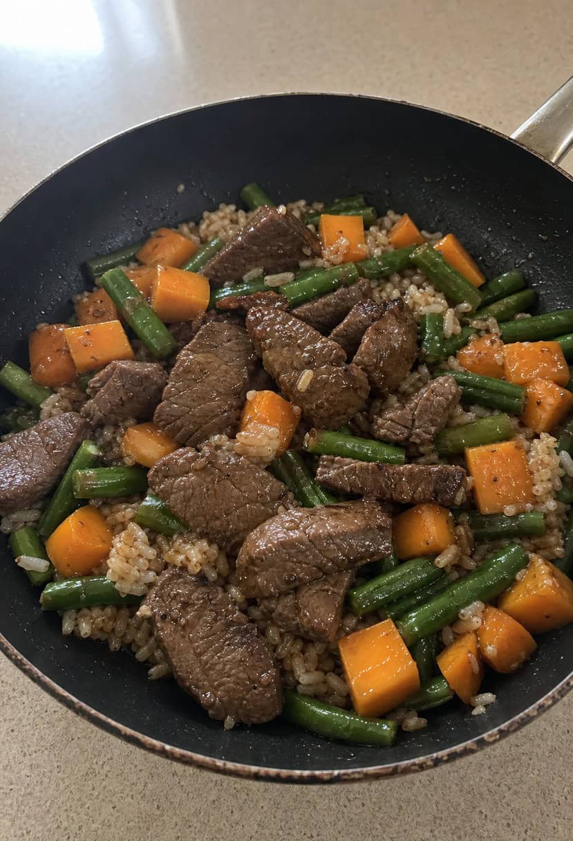 A sizzling skillet filled with Korean beef, vegetables, and rice, with steam rising