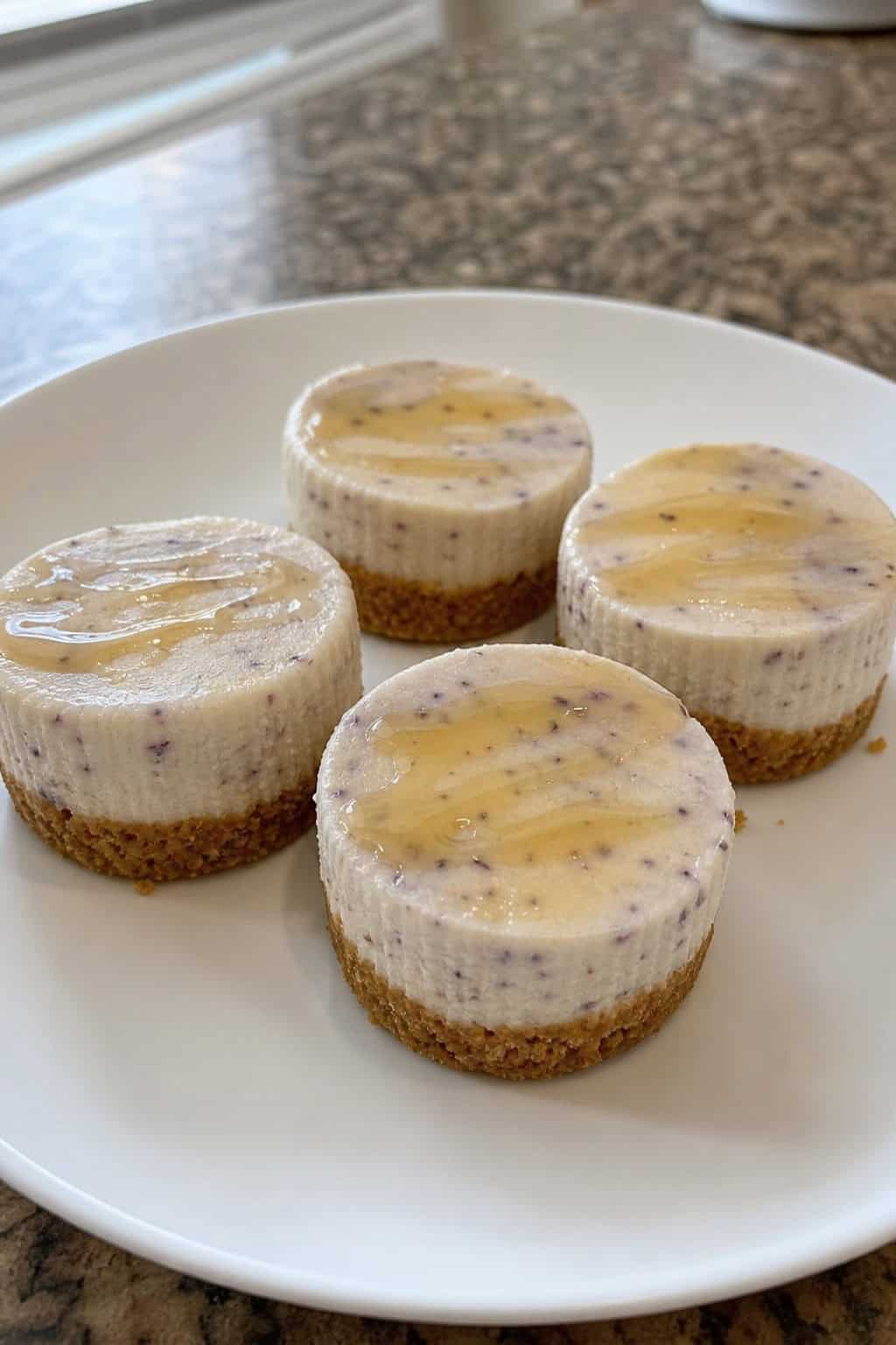 Several mini lavender honey cheesecakes on a wooden board, garnished with lavender sprigs and honey drizzle.