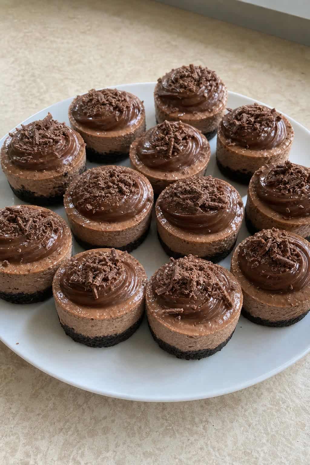 A group of mini Nutella cheesecakes on a wooden board with chocolate swirls and garnishes, set in a warm, festive party environment.