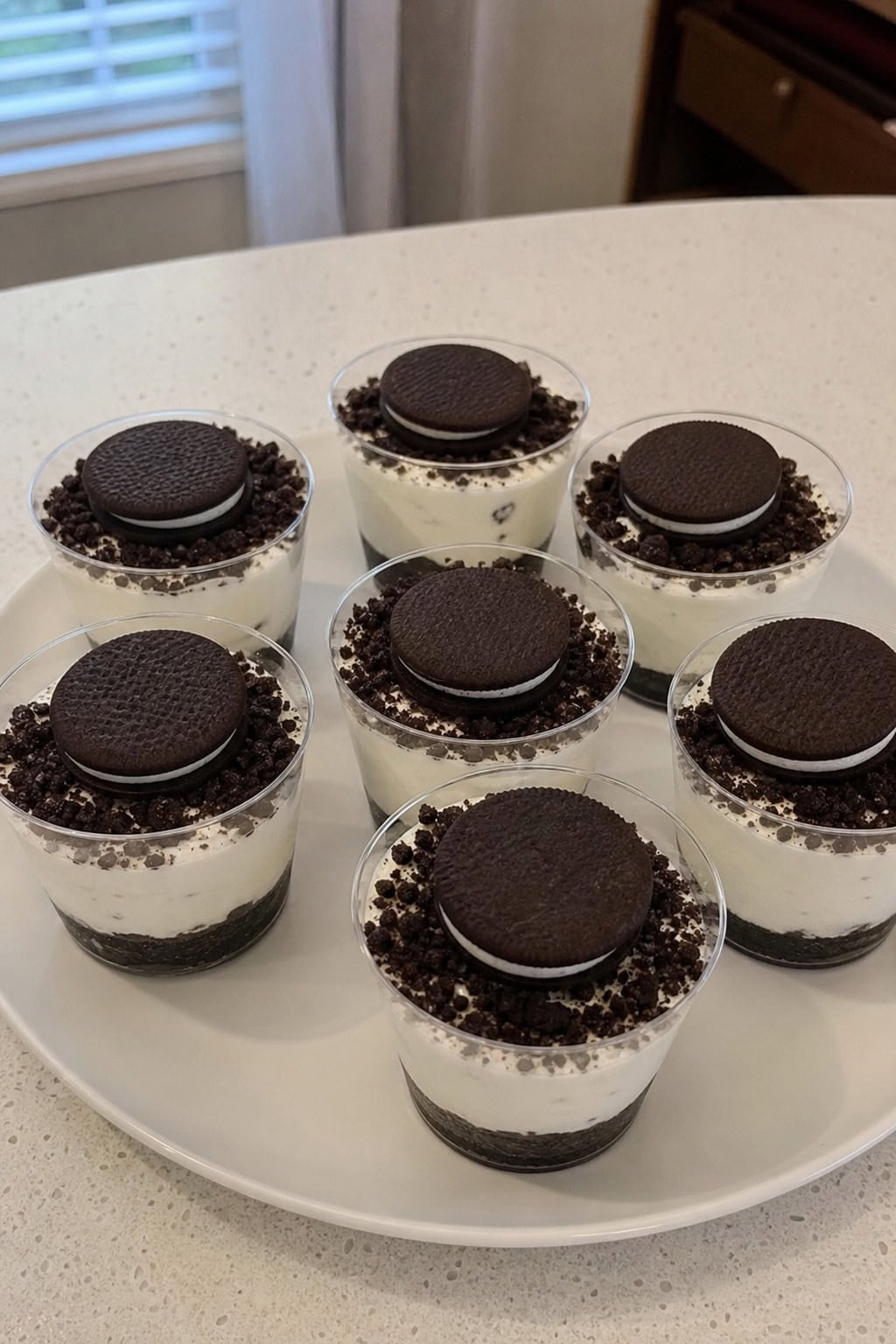 A platter of mini Oreo cheesecake cups topped with mini Oreo cookies, arranged for a party setting.