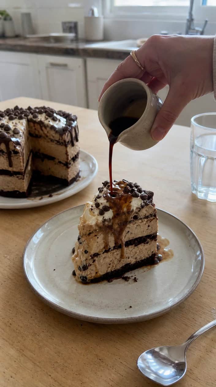 An espresso affogato ice cream cake on a wooden table with coffee beans and a glass of espresso nearby.
