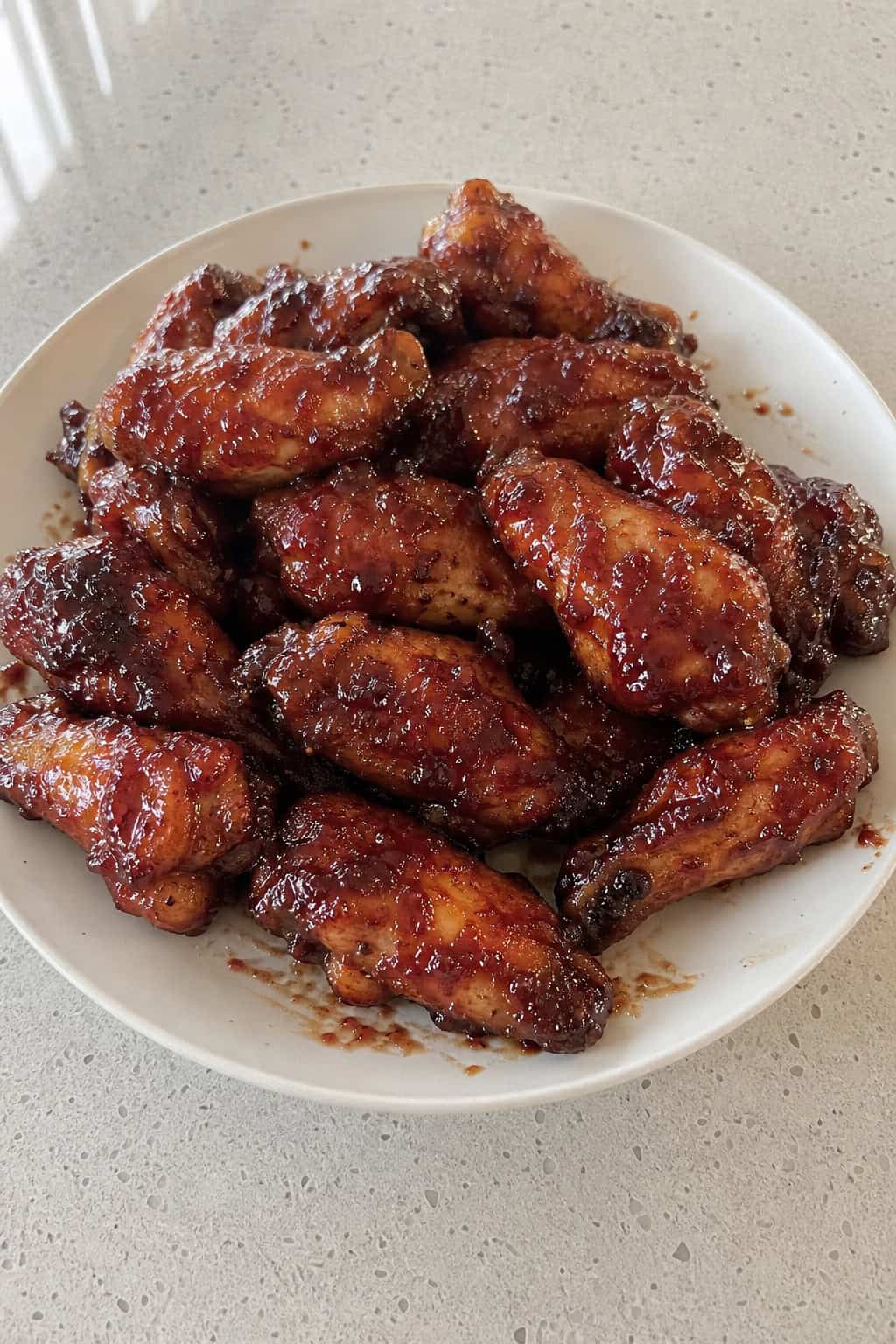Close-up of glazed chicken wings garnished with fresh mint leaves on a plate.
