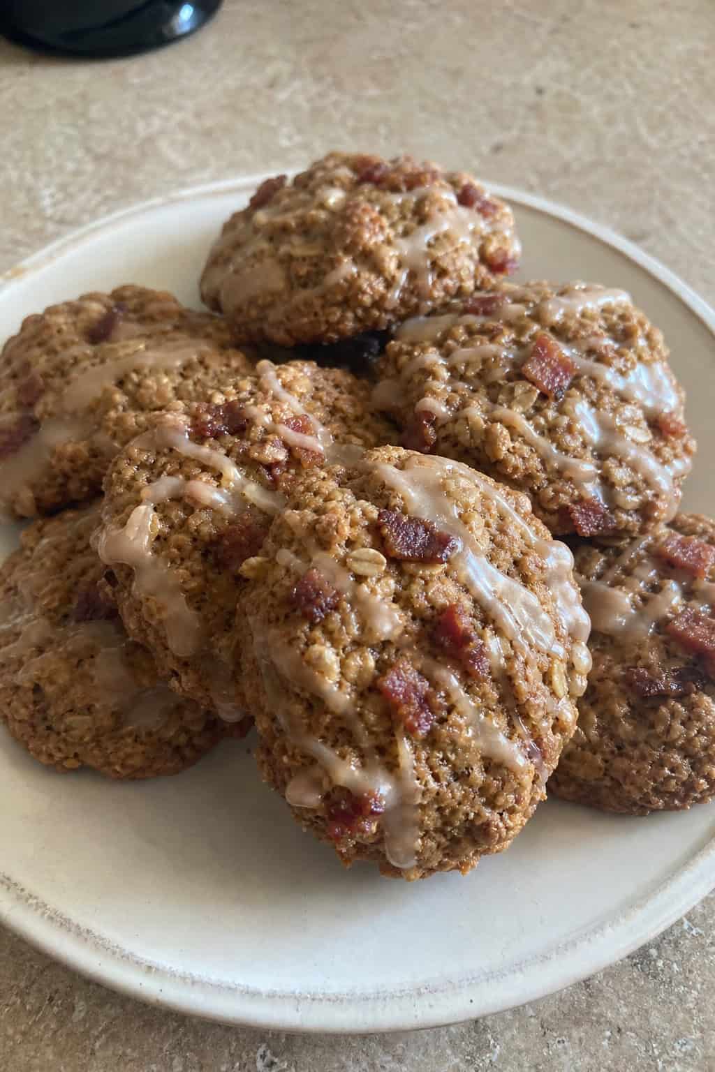 A platter of pumpkin spice bacon oatmeal cookies surrounded by autumn decorations like small pumpkins and cinnamon sticks.