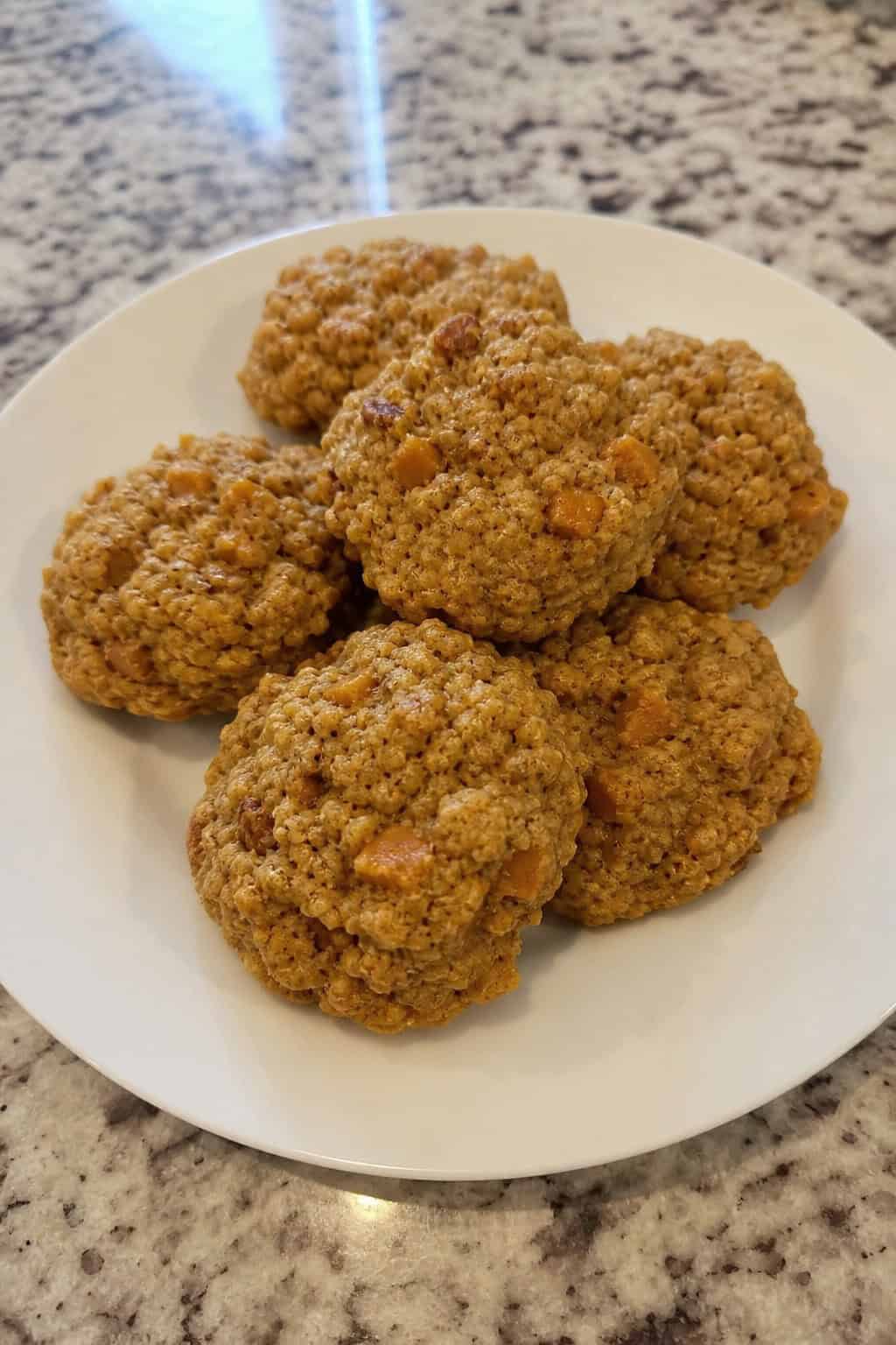 Freshly baked pumpkin spice drop cookies arranged on a wooden surface with autumn decorations in the background.