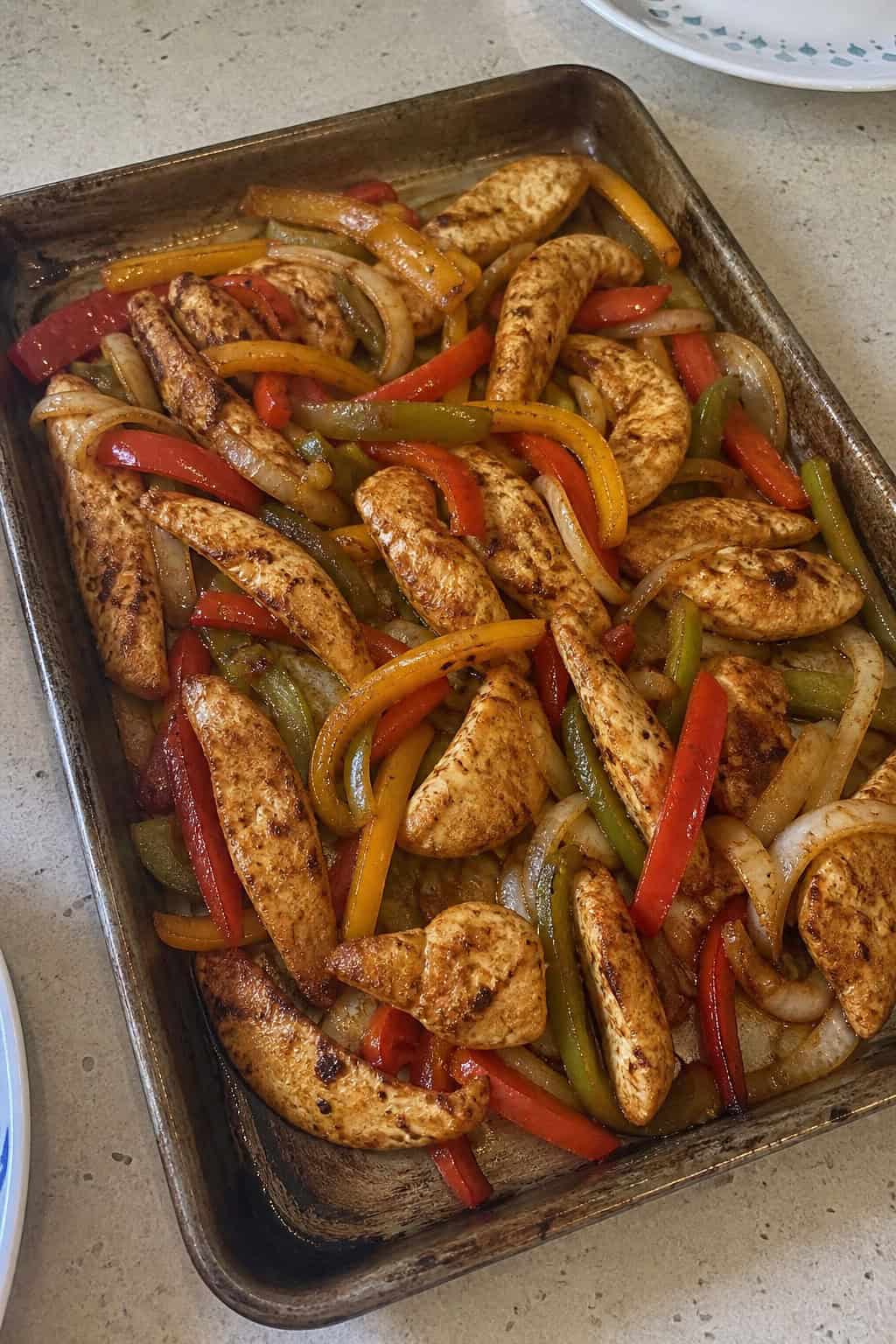 Sheet-pan chicken fajitas with colorful bell peppers and onions roasted together, garnished with fresh cilantro.