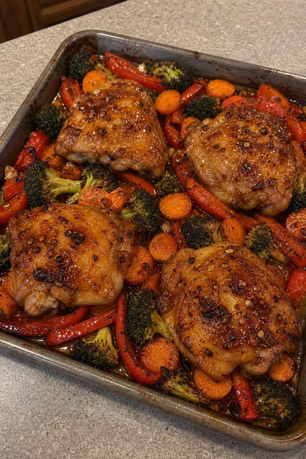 23 Honey Garlic Chicken Thigh Recipes You’ll Absolutely Love! 3 A sheet pan with honey garlic chicken thighs and roasted vegetables including carrots, broccoli, and red bell peppers.