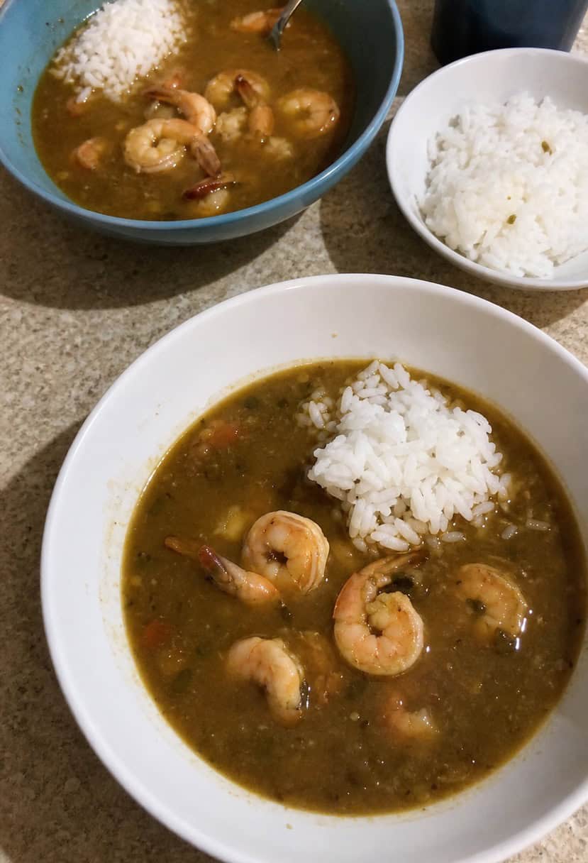 A steaming pot of shrimp gumbo surrounded by fresh ingredients and spices on a rustic kitchen counter