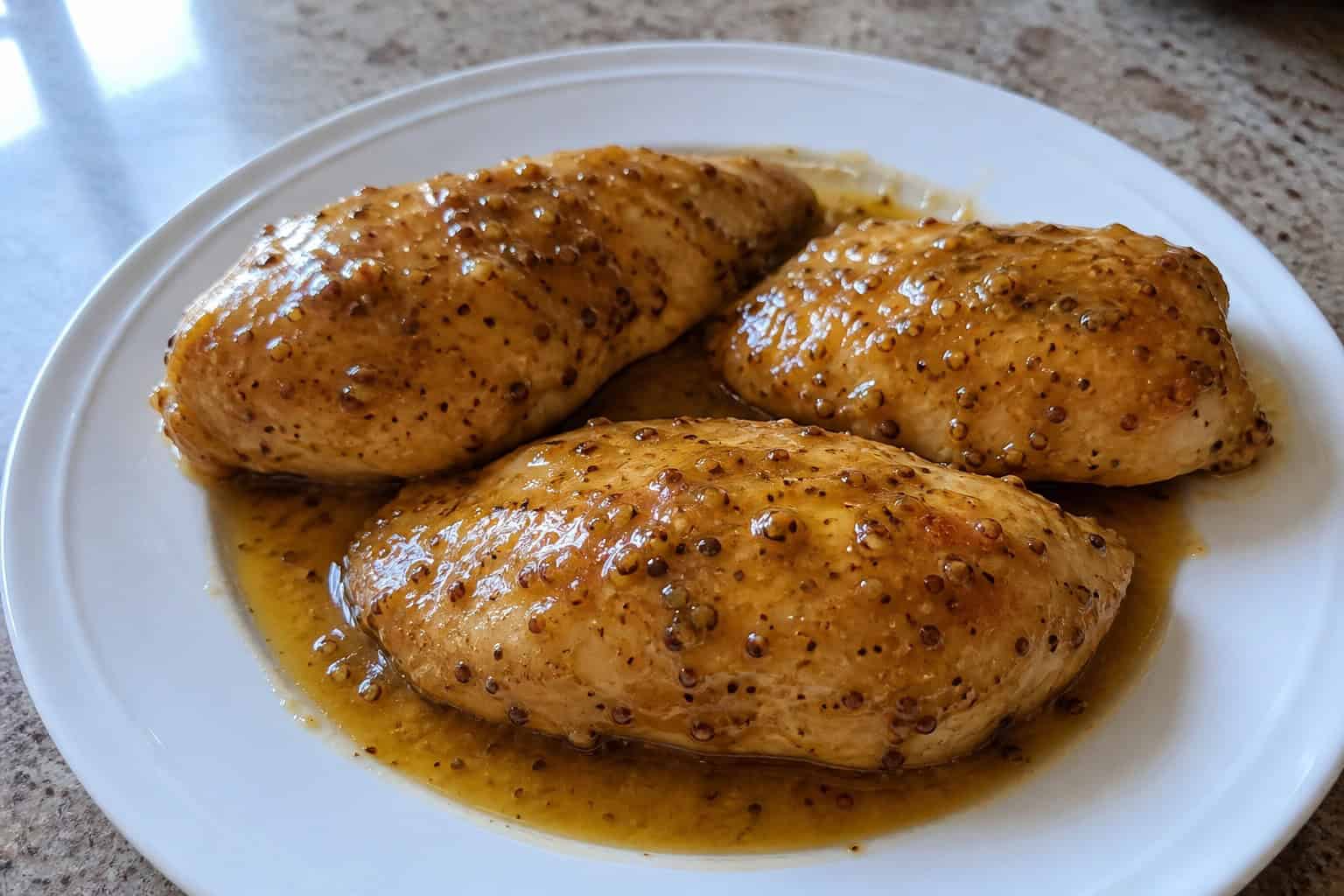 Close-up of glazed honey mustard chicken breasts in a slow cooker with fresh herbs and kitchen ingredients around.