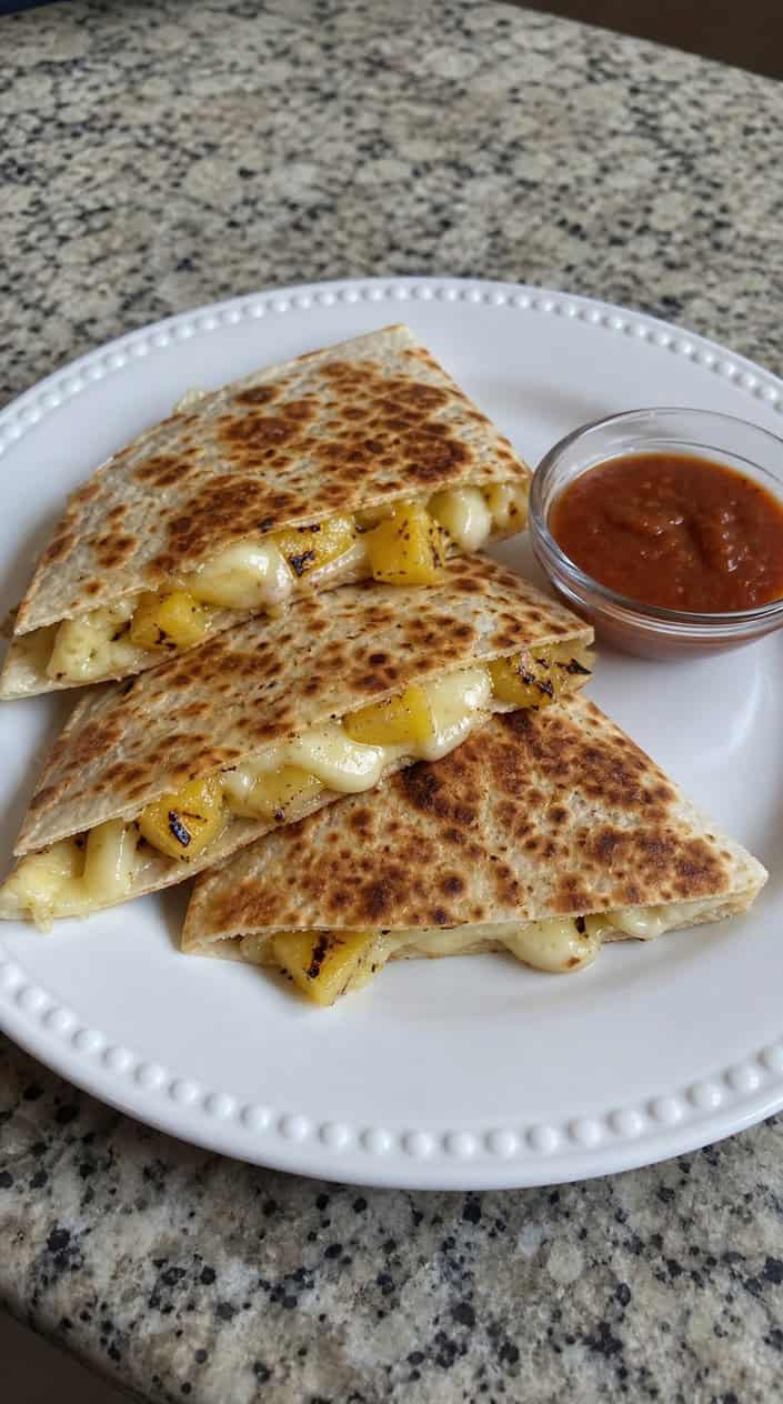 Golden quesadilla wedges on a wooden board with glossy caramelized pineapple chunks and a few scattered mint leaves.