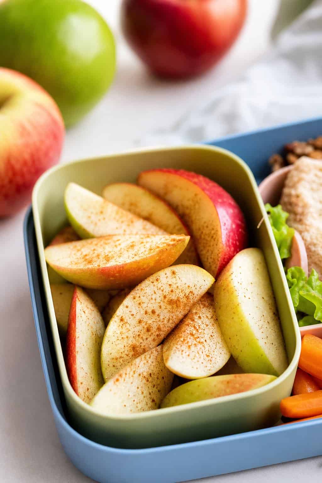 16 Easy Lunchbox Sides Kids Will Eat 2 Cinnamon-dusted apple slices arranged in a compartment of a lunchbox.