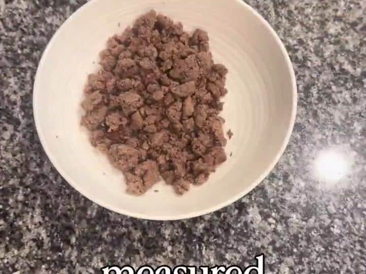 A white bowl contains a measured portion of cooked ground beef sitting alone on the counter.
