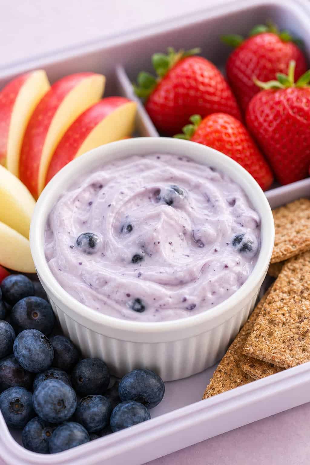 16 Easy Lunchbox Sides Kids Will Eat 9 A ramekin of blueberry yogurt dip surrounded by blueberries, fruit slices, and crackers.