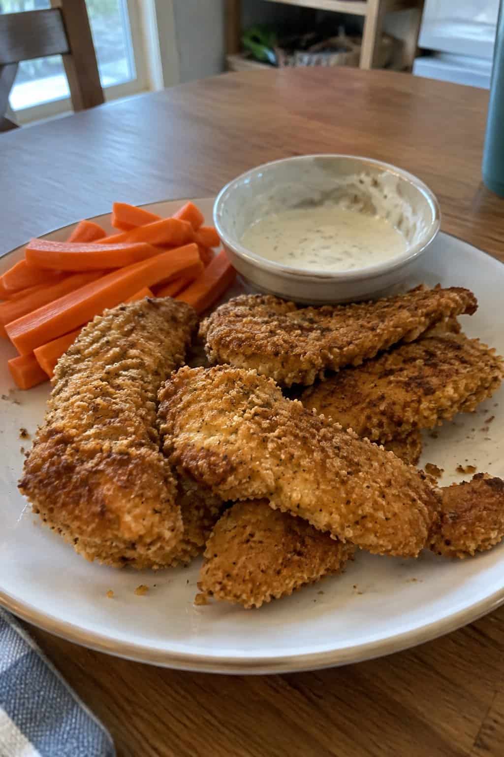Golden chicken tenders served with dipping sauce and a simple side.