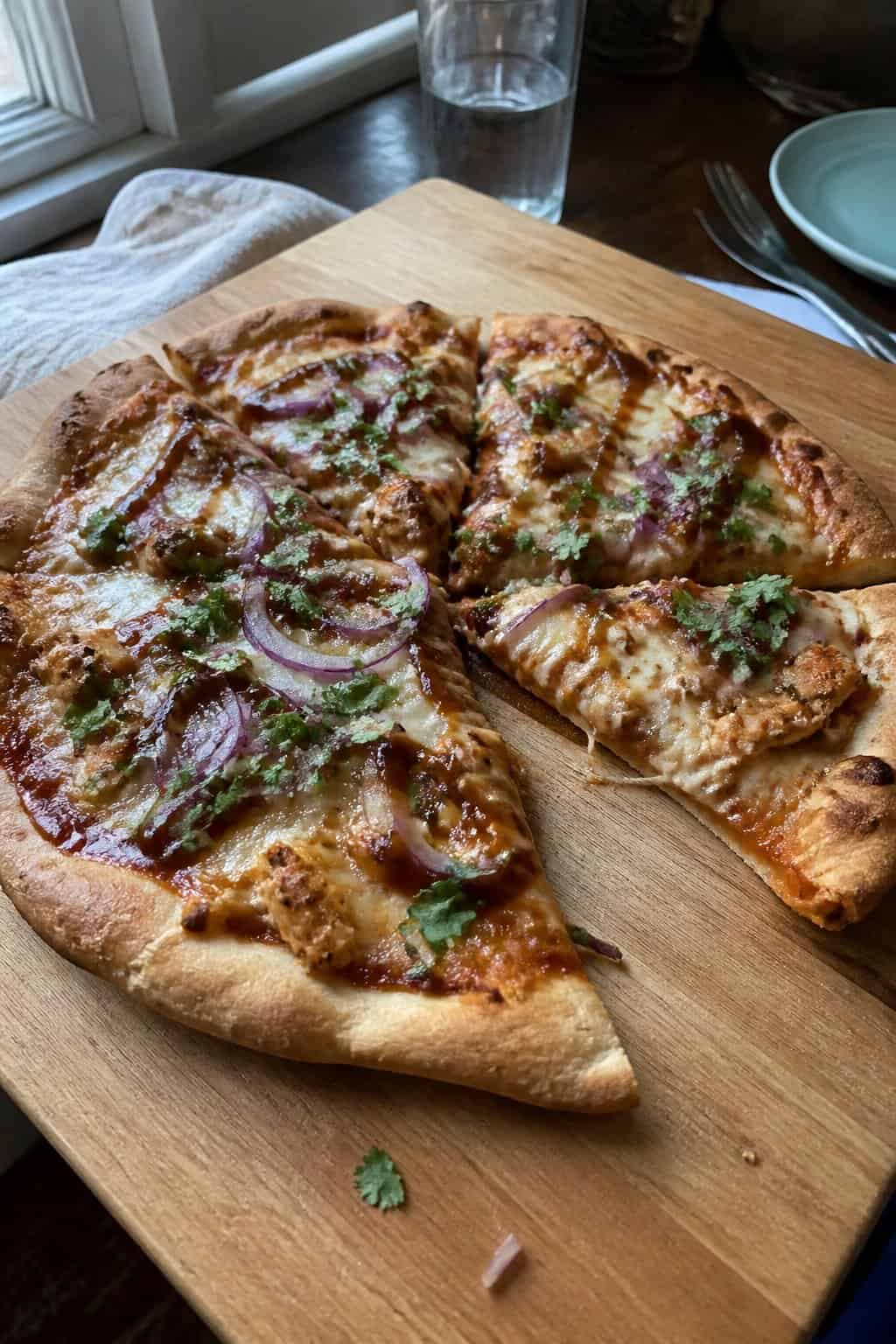 20 Copycat Chicken Recipes for Restaurant Cravings at Home 16 A homemade barbecue chicken pizza with melted cheese, red onion, cilantro, and barbecue sauce on a kitchen table.
