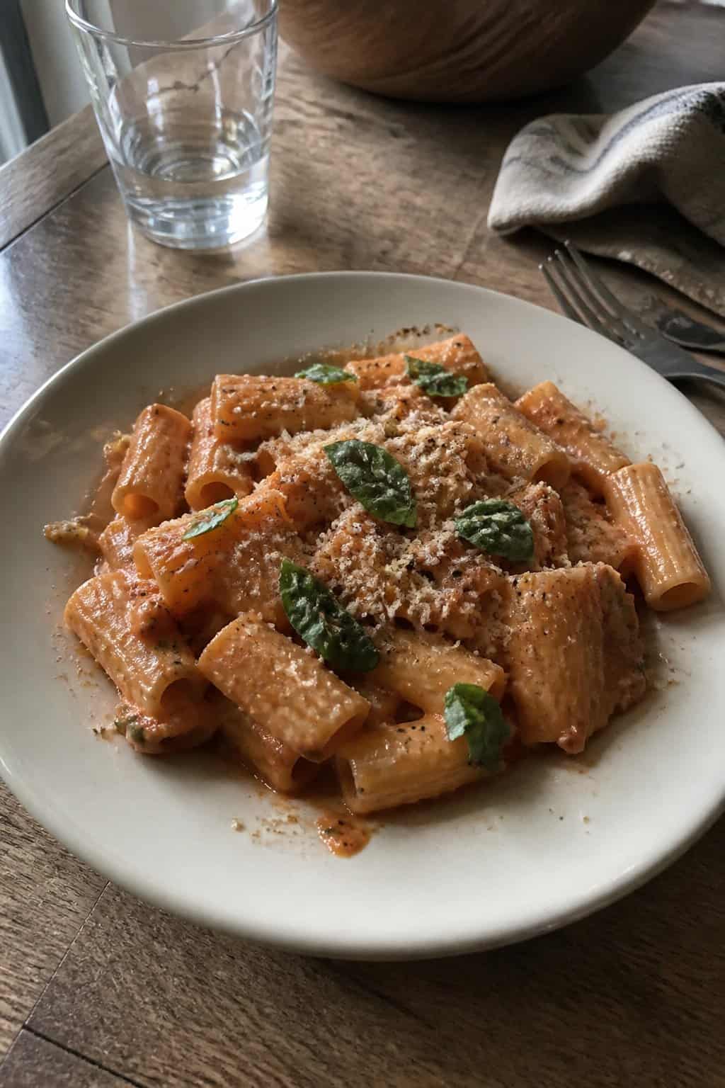 17 Pasta Dinners That Feel Fancy But Use Pantry Staples 7 A plate of creamy tomato pasta topped with torn basil leaves and grated cheese