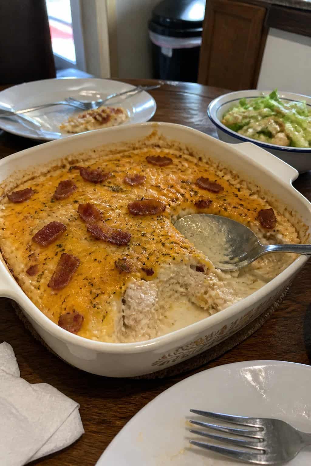 A creamy chicken, bacon, and ranch casserole served in a baking dish on a dining table.
