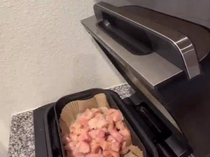 Diced raw chicken in a parchment-lined air fryer basket, ready to cook at 400 degrees.