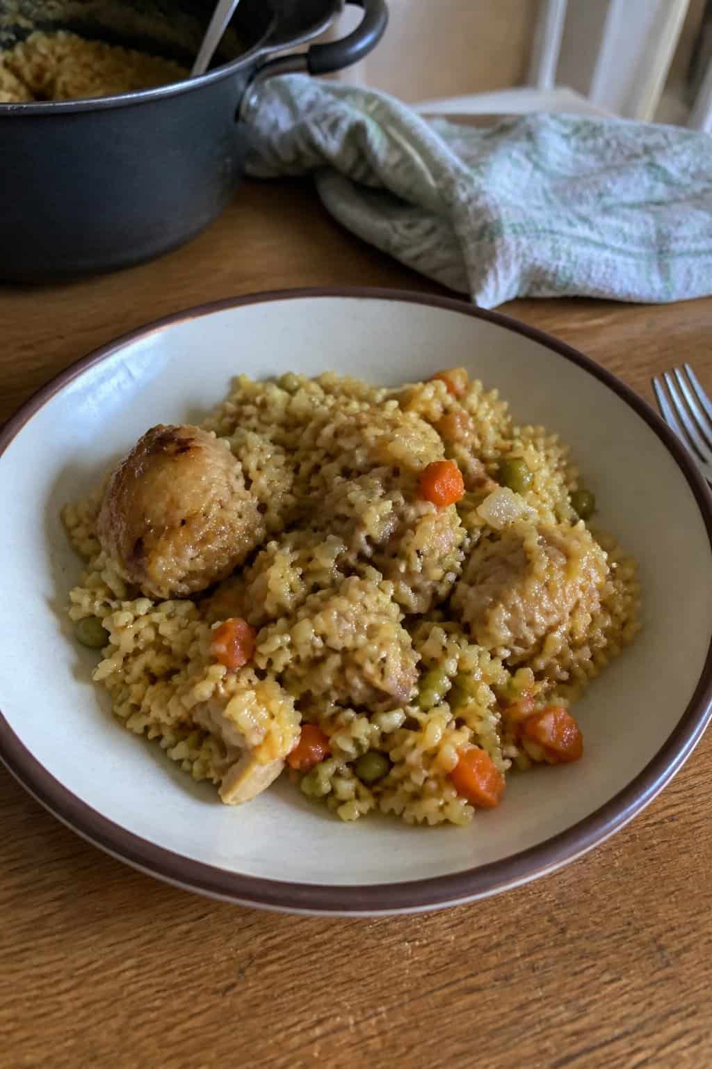 17 Budget Dinners That Use What You Already Bought 4 A bowl of chicken and rice with peas and carrots on a wood kitchen table.