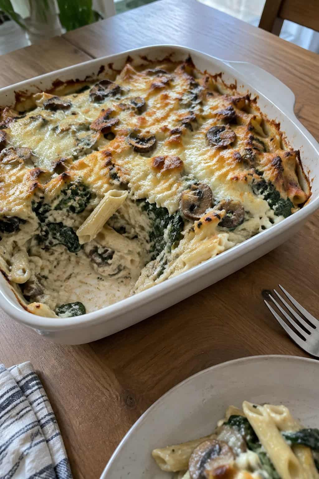 A serving of creamy mushroom and spinach pasta bake on a plate.