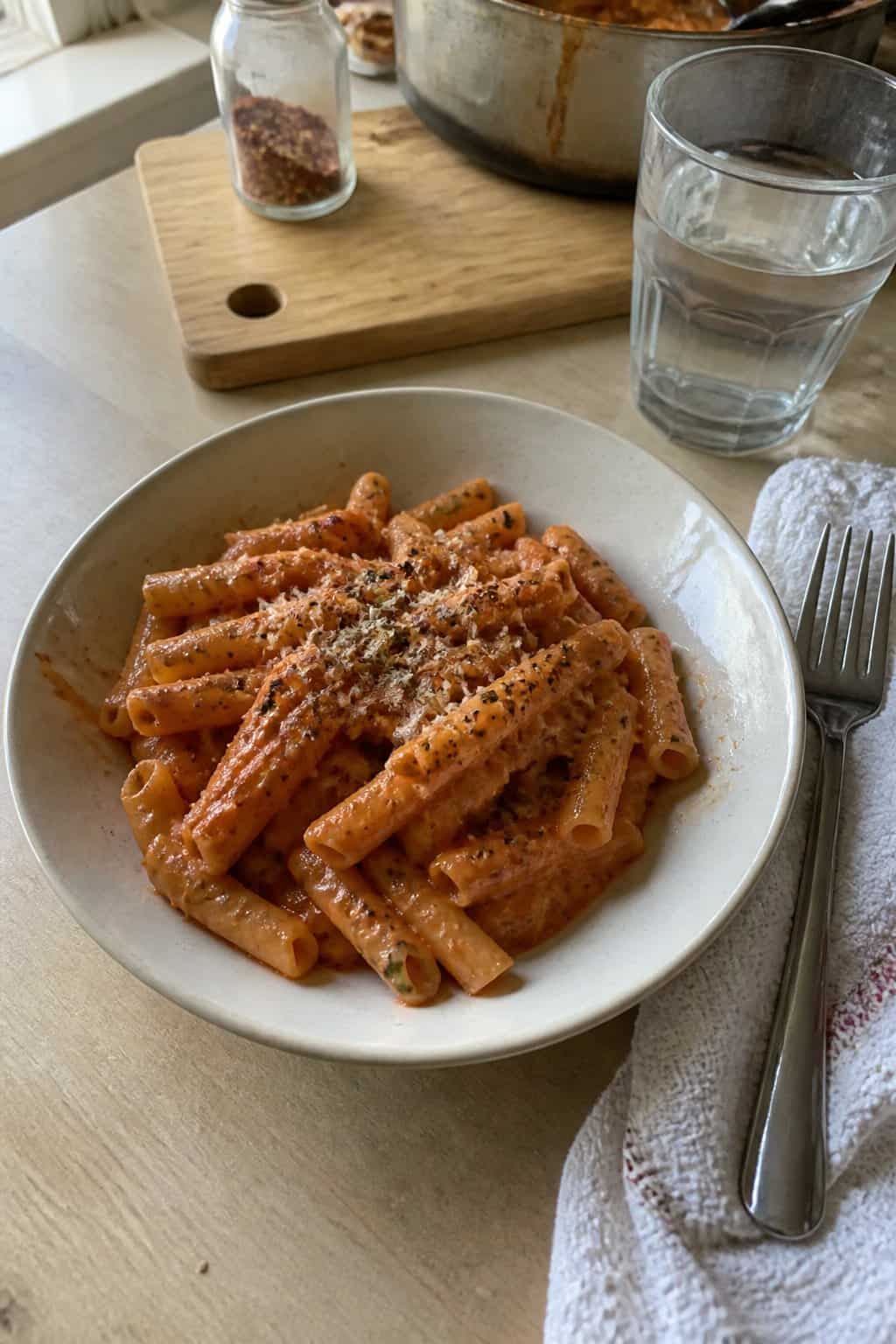 17 Budget Dinners That Use What You Already Bought 3 A bowl of creamy tomato pasta with fresh herbs and cracked black pepper on a kitchen table.