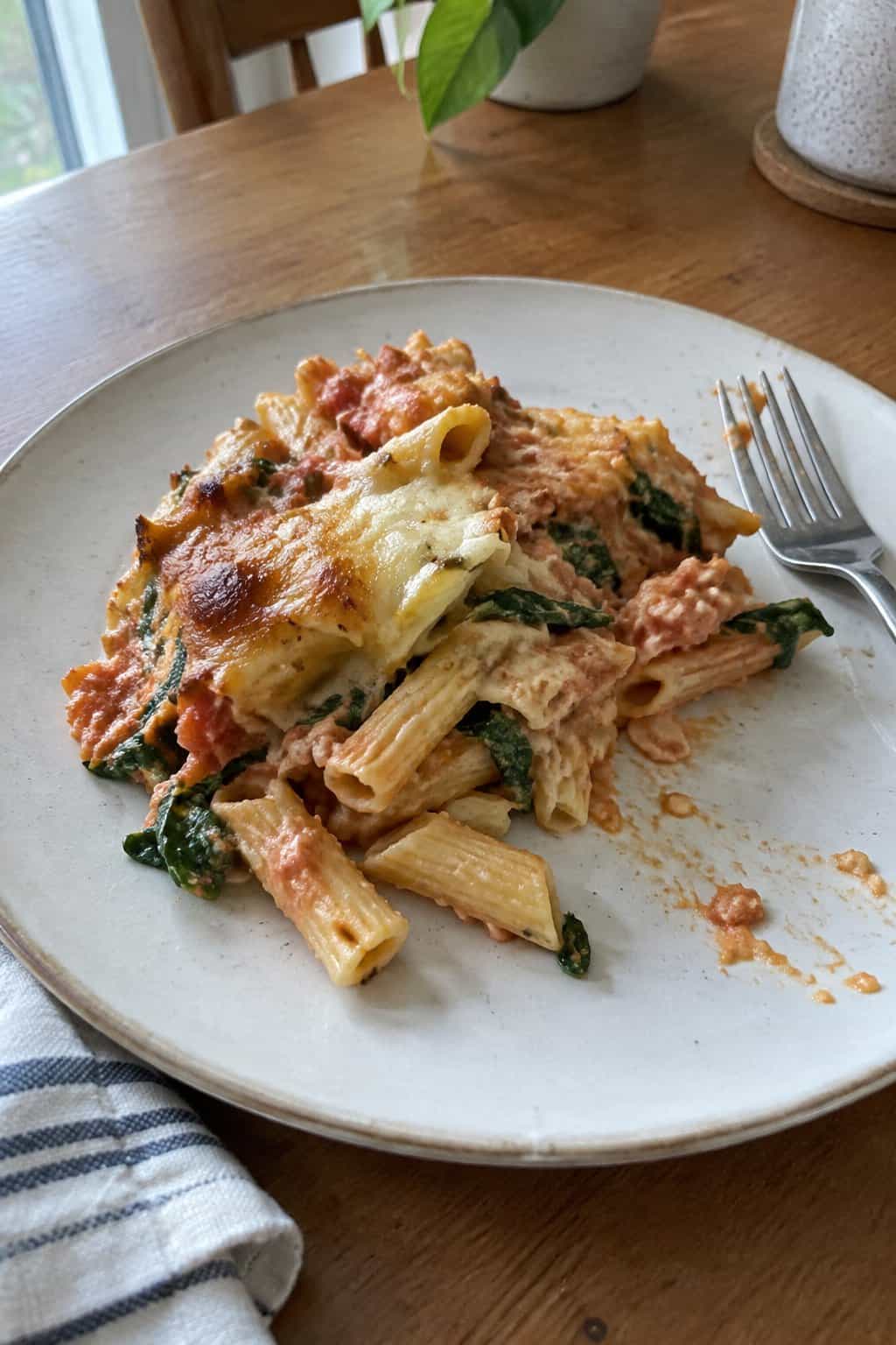 A serving of creamy tomato and spinach pasta bake on a plate.