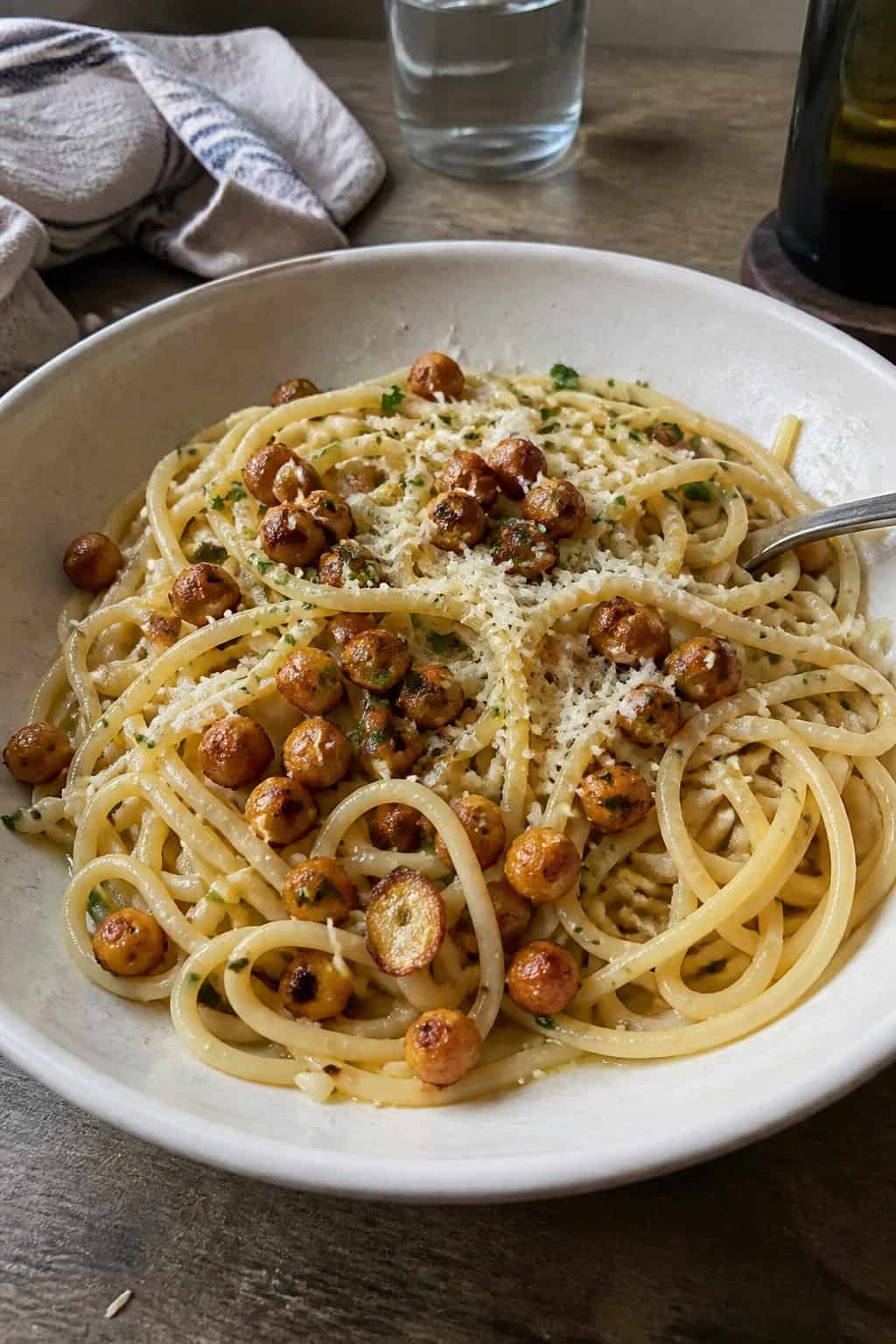 17 Pasta Dinners That Feel Fancy But Use Pantry Staples 8 A plate of garlic spaghetti topped with golden crispy chickpeas, grated Parmesan, and chopped parsley
