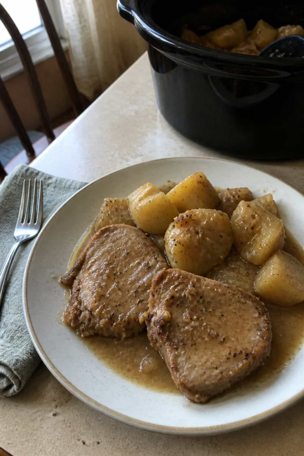 A plate of pork chops and potatoes with gravy on a kitchen table.