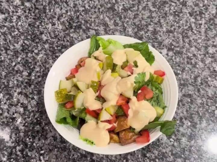 Finished healthy burger bowl with lettuce, tomato, pickles, potatoes, beef and creamy burger sauce.