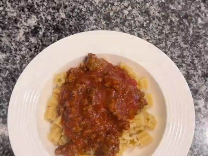 Weeknight Ground Beef Pasta with Quick Garlic Toast 5 A white plate shows star-shaped pasta topped with meat sauce next to a slice of toasted garlic bread.