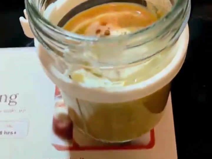 10-Minute Pumpkin Chia Pudding With Hemp Hearts and Yogurt 5 A clear glass jar holds the finished layered pumpkin chia pudding with a light top layer and syrup drizzled around the rim.