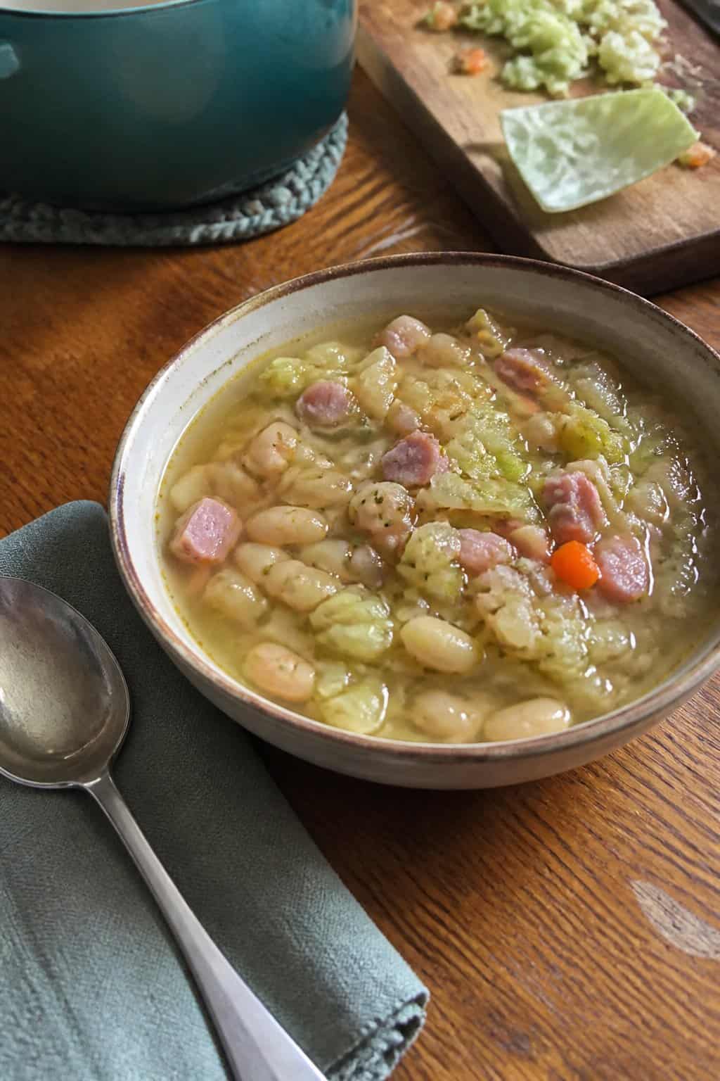 Ham Soup Recipes for Chilly Nights 9 A bowl of ham, cabbage, and white bean soup on a kitchen table.