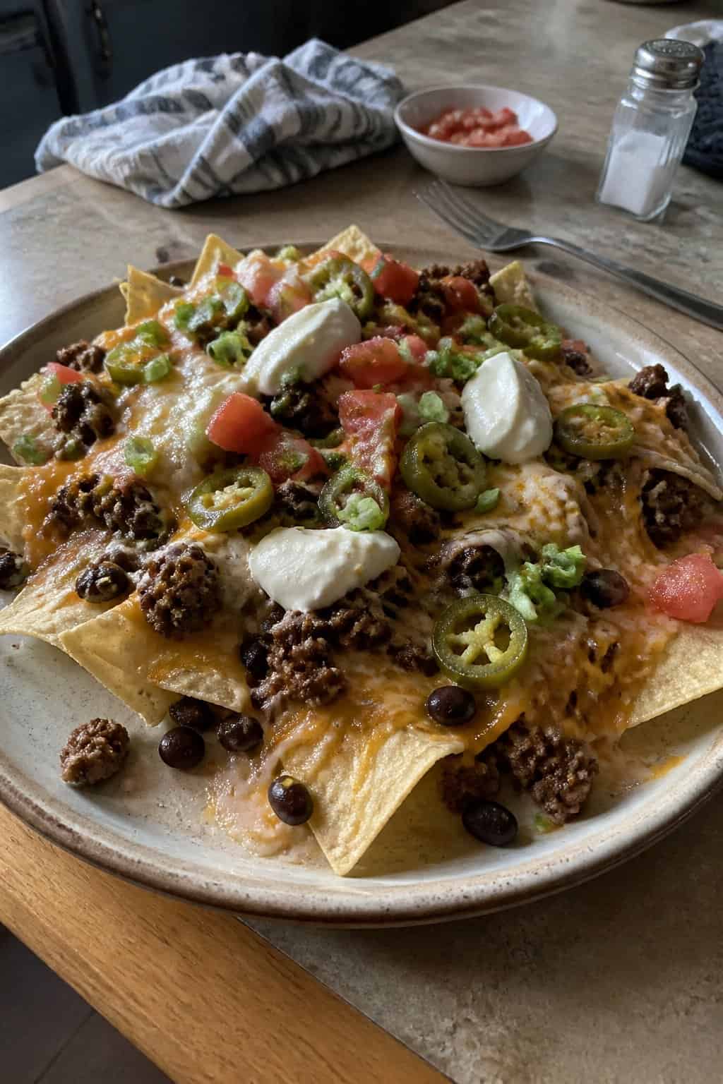 17 Budget Dinners That Use What You Already Bought 14 A sheet pan of tortilla chips loaded with taco meat, melted cheese, black beans, tomatoes, jalapeños, and sour cream.