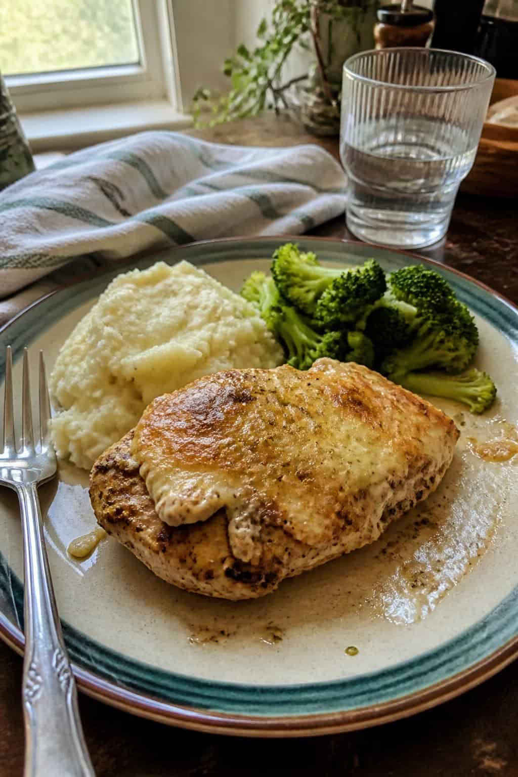 20 Copycat Chicken Recipes for Restaurant Cravings at Home 13 A plate of Parmesan-crusted chicken with mashed potatoes and broccoli on a kitchen table.