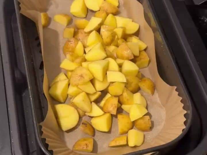 Cut baby golden potatoes in a parchment-lined air fryer basket before cooking.