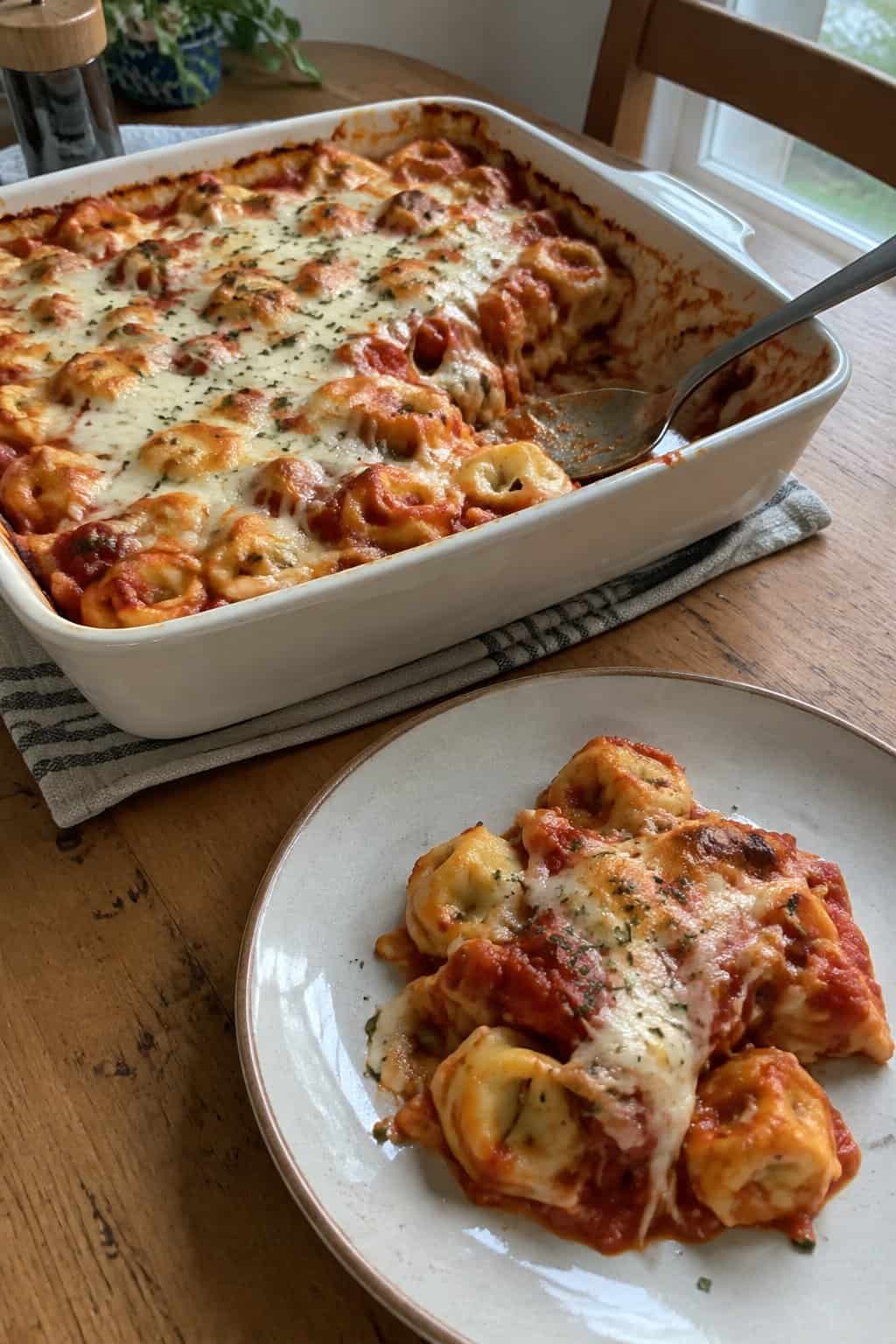 A dish of baked cheese tortellini in tomato sauce with melted cheese.