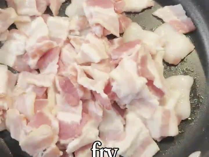 Raw bacon cut into bite-sized pieces sitting in a frying pan before cooking.