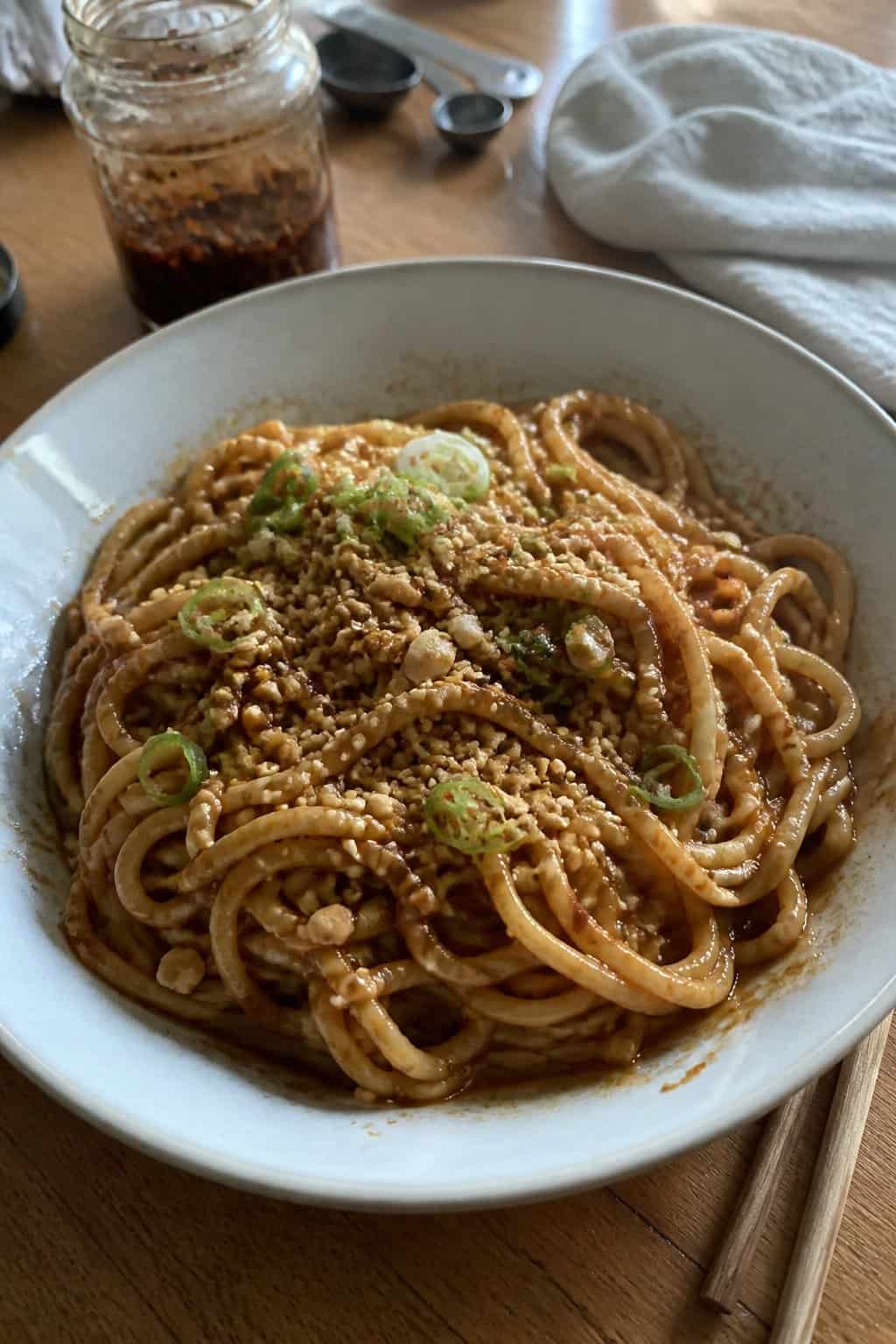 17 Pasta Dinners That Feel Fancy But Use Pantry Staples 10 A bowl of peanut-chili noodles topped with sliced scallions, crushed peanuts, and red chili flakes