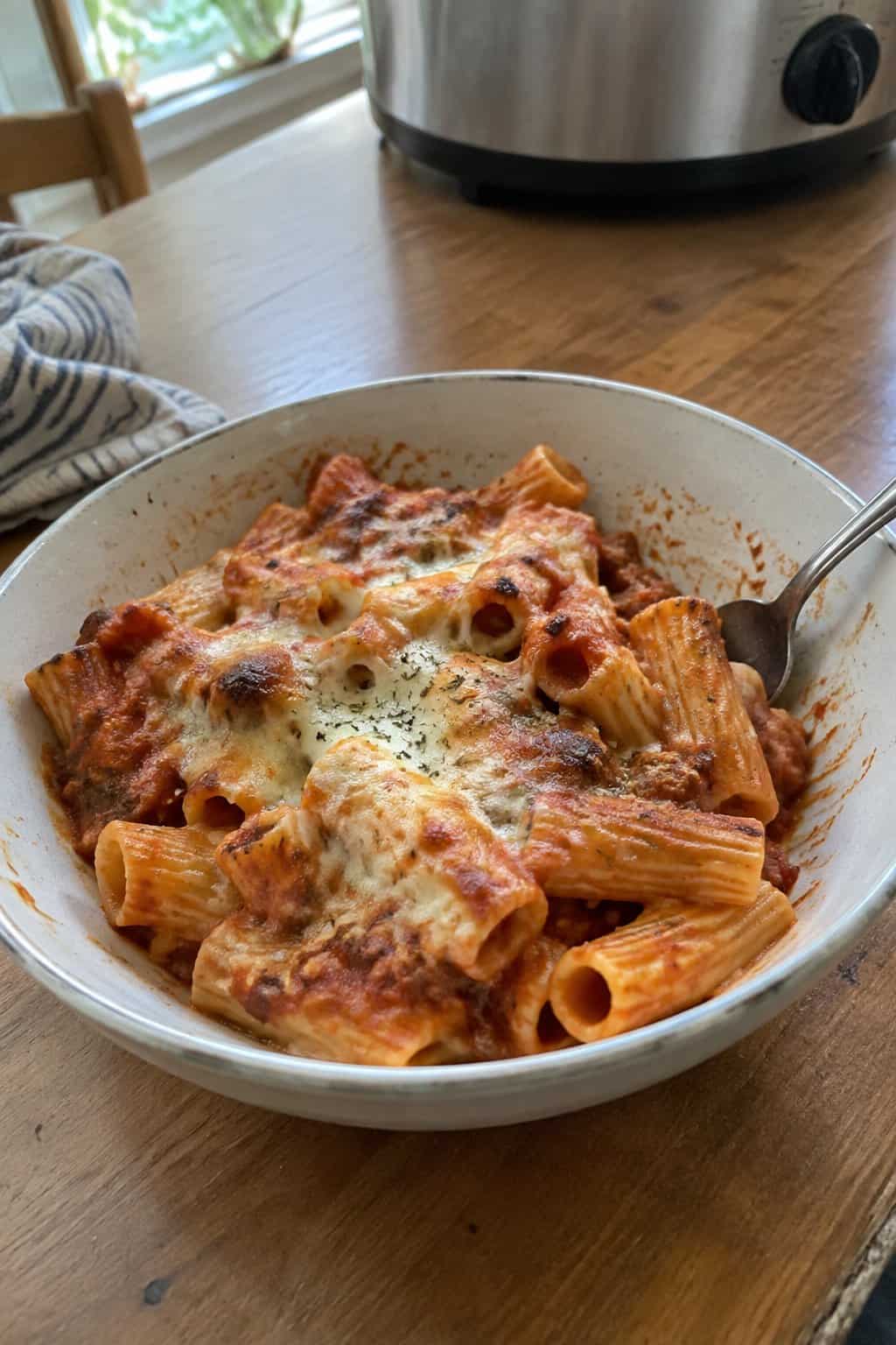 Rigatoni tubes baked in bubbling tomato sauce with a golden layer of melted mozzarella on top.