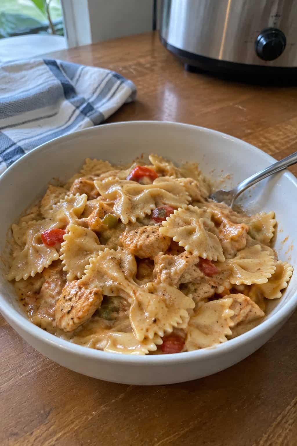 Bow-tie farfalle pasta in a creamy, reddish Cajun-spiced sauce with chicken pieces.